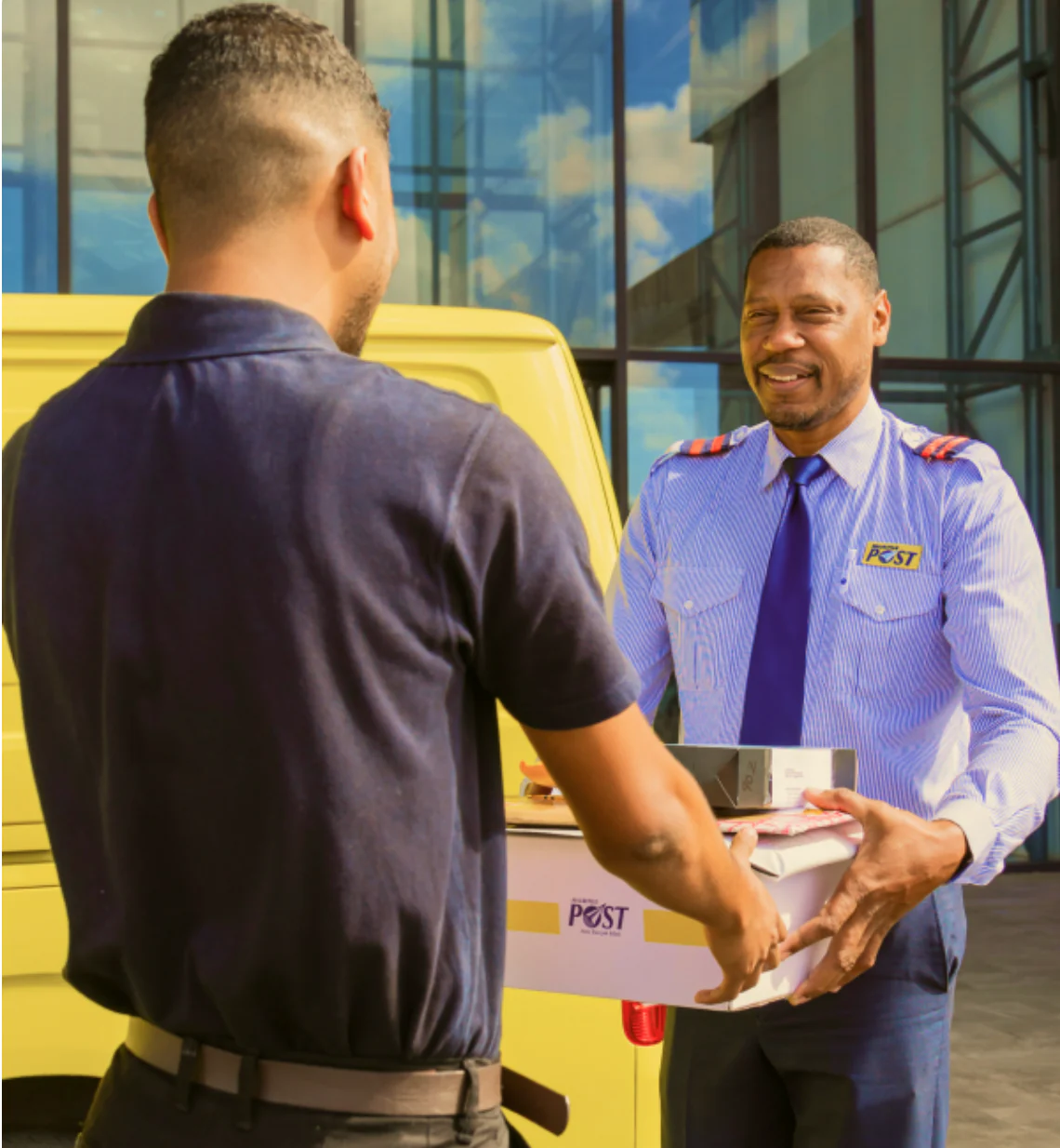 A Mauritius Post employee handing a parcel to a customer